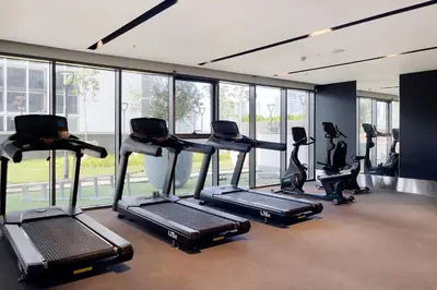 a gym with several tread machines in a room with windows at 10 Mins to Dubai Mall1BRBusiness Bay Heaven in Dubai