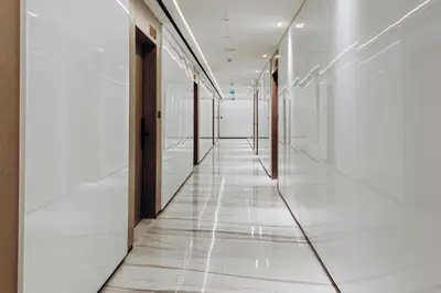 a corridor in a building with white floors and glass walls at 1BR Cozy and NEW brand JVC in Dubai
