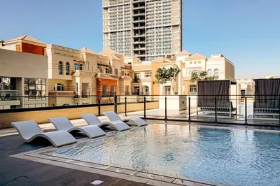 a swimming pool with white chairs on top of a building at 1BR Cozy and NEW brand JVC in Dubai