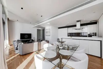 a living room with a glass table and white chairs at Bluewaters Sea View 2BR Pool & Gym & Beachfront in Dubai