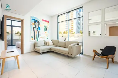 a living room with a couch and a table at Blue Breeze - Elegant 1BR with Private Jacuzzi & Terrace in JVC in Dubai
