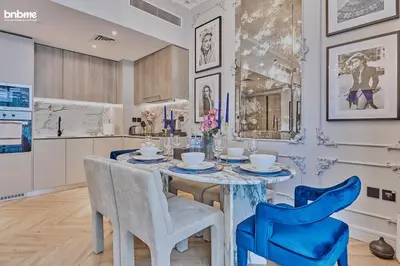a dining room with a table and blue chairs at bnbmehomes - Oxford Terraces in Dubai