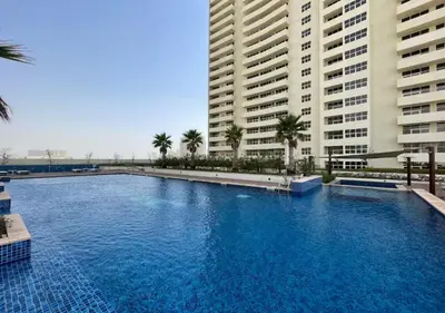a large swimming pool in front of two tall buildings at Bespoke Holiday Homes - High floor studio in Tower 108 JVC in Dubai