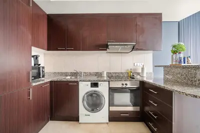 a kitchen with wooden cabinets and a washing machine at Silkhaus Cozy Studio at Sky Gardens-Heart of DIFC in Dubai