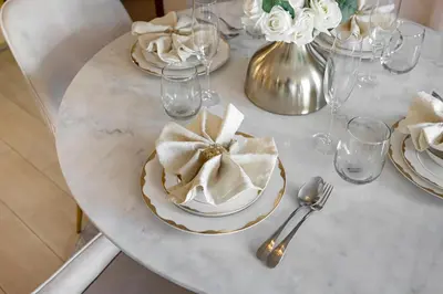 a white table with plates and silverware and flowers at Durrani Homes - Azure 2BR with Burj Khalifa and Fountain View in Dubai
