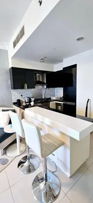a kitchen with a white counter and white chairs at Superb 1 BR apt next to Burj Khalifa and Dubai mall in Dubai