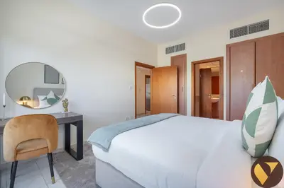 a bedroom with a bed and a desk and a mirror at Vogue The Greens Al Dhafrah near Mall of the Emirates, One Bedroom Apartment with Balcony and vibrant community view, Access to all Amenities in Dubai
