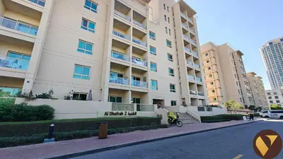 an apartment building with a motorcycle parked in front of it at Vogue The Greens Al Dhafrah near Mall of the Emirates, One Bedroom Apartment with Balcony and vibrant community view, Access to all Amenities in Dubai
