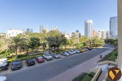 a city street with cars parked in a parking lot at Vogue The Greens Al Dhafrah near Mall of the Emirates, One Bedroom Apartment with Balcony and vibrant community view, Access to all Amenities in Dubai