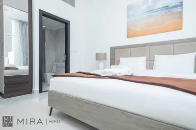 a bedroom with a large white bed and a bathroom at Mira Holiday Homes - Cosy 1 bedroom close to metro Al Furjan in Dubai