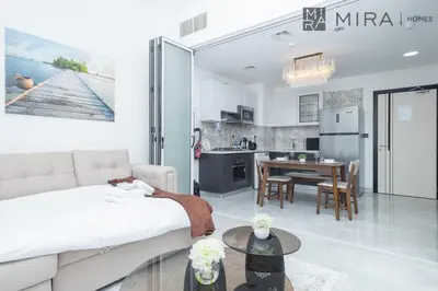 a living room and kitchen with a couch and a table at Mira Holiday Homes - Cosy 1 bedroom close to metro Al Furjan in Dubai