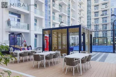a patio with tables and chairs in front of a building at Mira Holiday Homes - Cosy 1 bedroom close to metro Al Furjan in Dubai