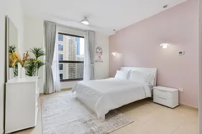 a white bedroom with a large bed and a window at Savis Home Oceanfront Serenity and Marina Views in Dubai