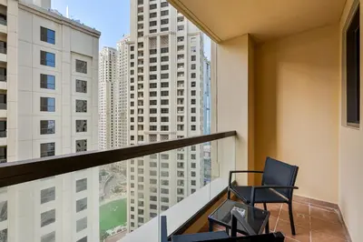 a chair on a balcony with a view of tall buildings at Savis Home Oceanfront Serenity and Marina Views in Dubai