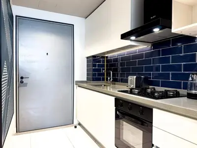 a kitchen with white counters and a blue tiled wall at Select Stay-Studio in MAG 318 - Minutes to Dubai Mall in Dubai