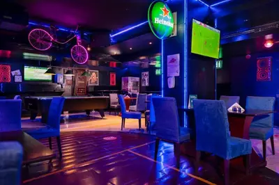 a bar with blue chairs and a ping pong table at Manhattan Avenue Hotel in Dubai