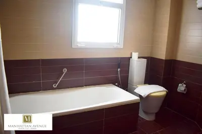 a bathroom with a tub and a toilet and a window at Manhattan Avenue Hotel in Dubai