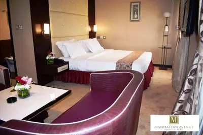a hotel room with a bed and a table and a couch at Manhattan Avenue Hotel in Dubai