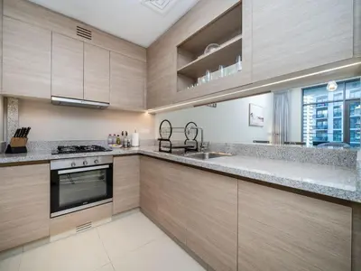 a kitchen with wooden cabinets and a stove top oven at Tranquil 1 Bedroom Dubai Hills Escape in Dubai