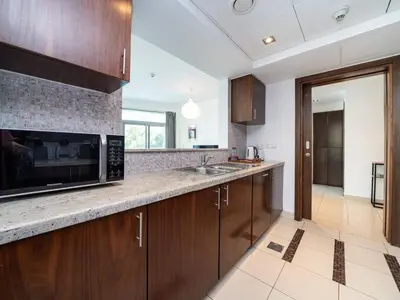 a kitchen with wooden cabinets and a microwave at Bright 1-Bedroom with Marina Infinity Pool in Dubai