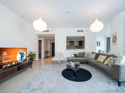 a living room with a couch and a tv at Bright 1-Bedroom with Marina Infinity Pool in Dubai