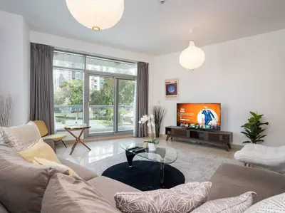 a living room with a couch and a tv at Bright 1-Bedroom with Marina Infinity Pool in Dubai