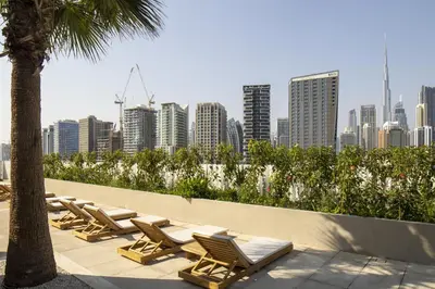 a row of chaise lounge chairs and a city skyline at Modern Studio, Burj Views - Business Travelers in Dubai