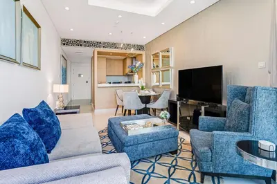 a living room with blue furniture and a tv at 2 Bedrooms with Iconic Burj Khalifa Views Stay in Dubai