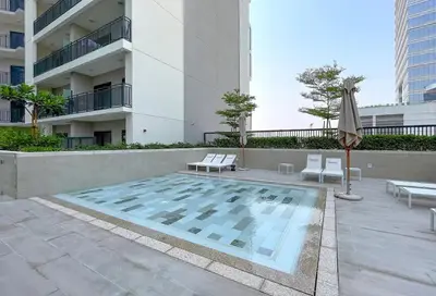 a swimming pool with two chairs and an umbrella and a building at Luxurious Pool View 1BHK, Zada Tower in Dubai