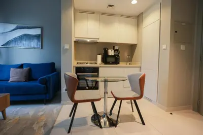 a kitchen and a living room with a table and chairs at Luxurious Pool View 1BHK, Zada Tower in Dubai