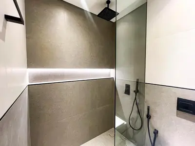 a shower with a glass door in a bathroom at Modern Studio in JVC - Pool, Gym & BBQ Access in Dubai