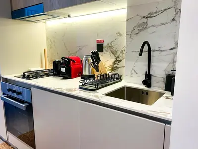 a kitchen with white counters and a sink at Modern Studio in JVC - Pool, Gym & BBQ Access in Dubai