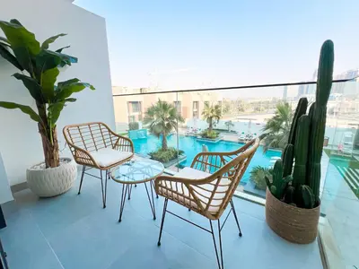 a balcony with a table and chairs and a pool at Modern Studio in JVC - Pool, Gym & BBQ Access in Dubai