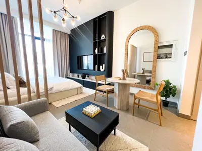 a bedroom with a bed and a living room with a table at Modern Studio in JVC - Pool, Gym & BBQ Access in Dubai