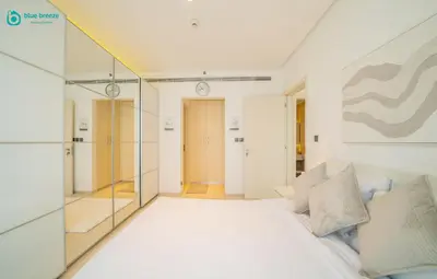 a bedroom with a white bed and a mirror at Blue Breeze - Modern Apt with Partial Marina Views & Balcony in Dubai