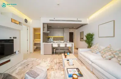 a living room with a white couch and a table at Blue Breeze - Modern Apt with Partial Marina Views & Balcony in Dubai
