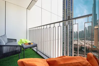 a balcony with an orange couch and a large window at Full Burj view & Direct Access to Dubai Mall in Dubai