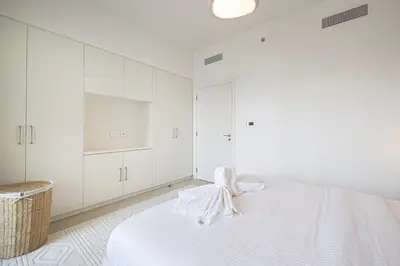 a white bedroom with white cabinets and a bed at Full Burj view & Direct Access to Dubai Mall in Dubai