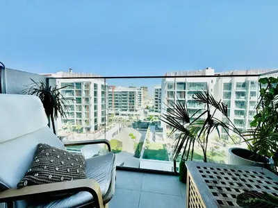 a balcony with a couch and a view of a city at Chic 1-BR in Azizi Riviera-Your Perfect Stay ! in Dubai