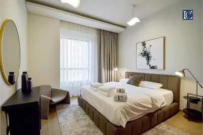a bedroom with a bed and a desk and a mirror at Luxury Escapes - Three-Bedroom Apartment with Lake View in Dubai