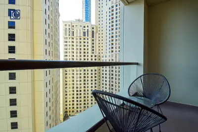 a chair on a balcony with a view of buildings at Luxury Escapes - Three-Bedroom Apartment with Lake View in Dubai
