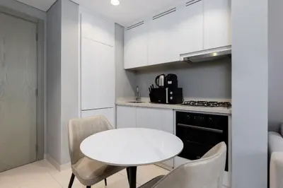 a white kitchen with a white table and chairs at Waves - Modern Apt with Balcony & Canal View in Business Bay in Dubai