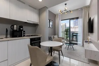 a kitchen and living room with a table and chairs at Waves - Modern Apt with Balcony & Canal View in Business Bay in Dubai
