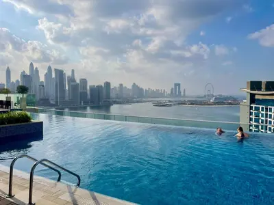 two people in a swimming pool with a city skyline at Great one bedroom apartment with infinity pool in Dubai