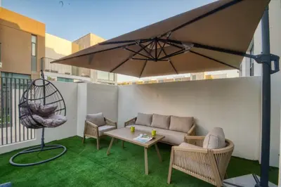 a patio with a couch and a table and an umbrella at Dubai dream villa Emaar in Dubai