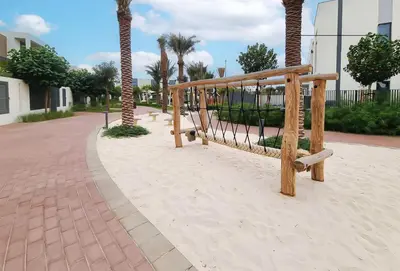 a wooden bench on a sidewalk with palm trees at Dubai dream villa Emaar in Dubai