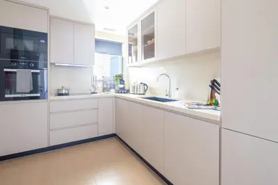 a white kitchen with white cabinets and a sink at Frank Porter - Zen Tower in Dubai