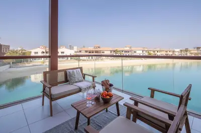 a balcony with a table and chairs and a pool at Frank Porter - Palm Views East in Dubai