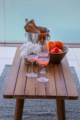 two wine glasses on a wooden table with a bowl of fruit at Frank Porter - Palm Views East in Dubai