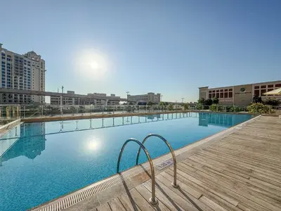 a large swimming pool with a wooden boardwalk and buildings at Frank Porter - Palm Views East in Dubai
